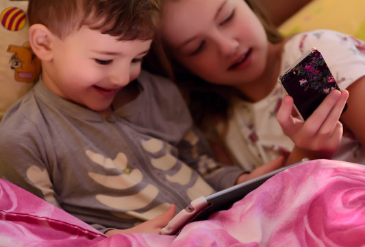 Blurred image. Children in bed playing with gadgets. Fuzzy image. Blurred image