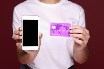 female hands holding credit card and a touch phone on the table in the office and making a purchase onlain - Image