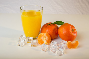 glass of orange juice and oranges on wooden table
