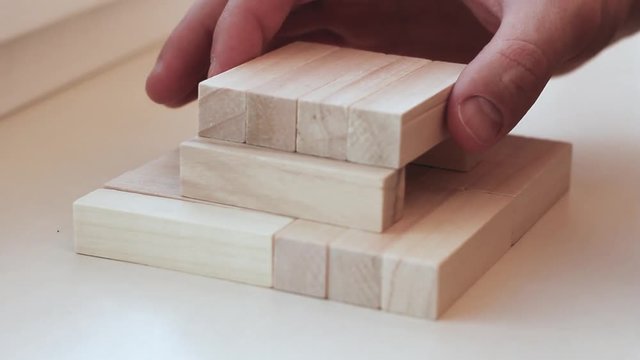 Close up hand holding blocks wood game jenga isolated on white background.