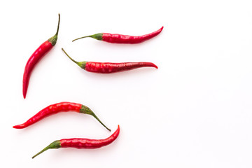 Red chili pods with green stems on white background. Top view.