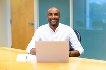 Happy young afro american businessman in the office with his laptop
