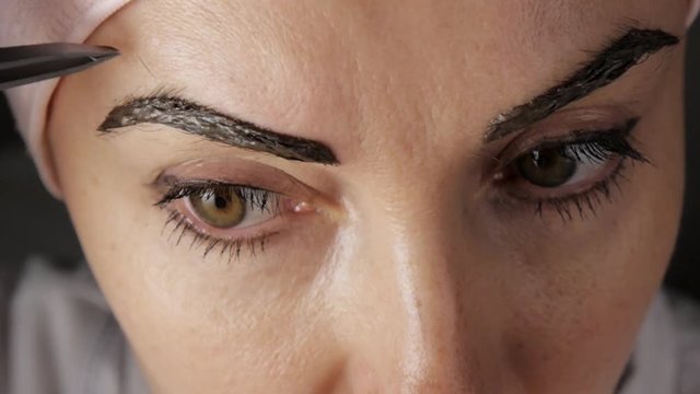 Eyebrows care. Attractive woman getting her eyebrows threaded. Close-up.