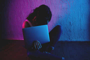 scared and sad female teenager with computer laptop suffering cyberbullying and harassment being...