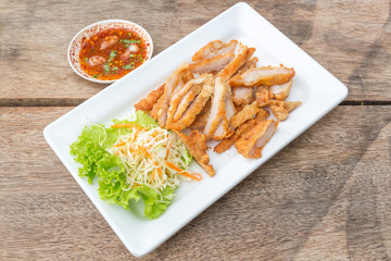 Fried Streaky Pork, vegetable and sauce (Thai food) in the white dish on the wooden table.