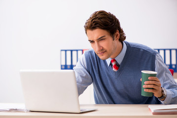 Young handsome employee working in the office 