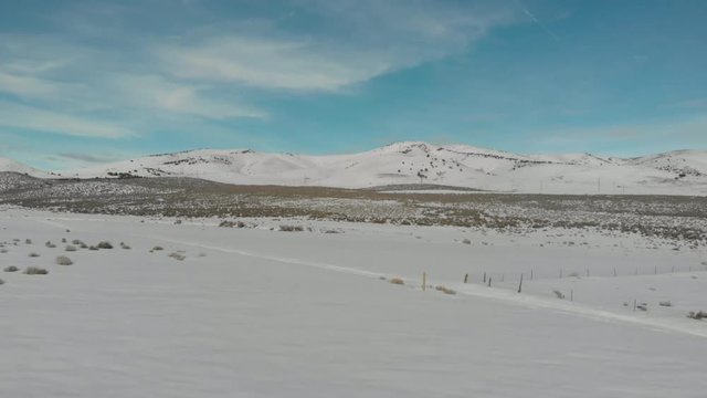 Aerial-Flying over snowy field to snow-covered hills