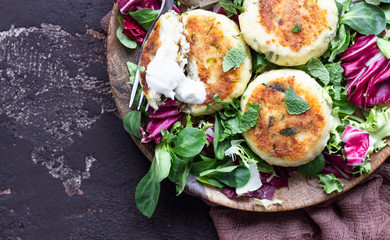 Cottage cheese pancakes or syrniki with cheese, green onion, dill and parsley served with salad mix and sour cream with mint.