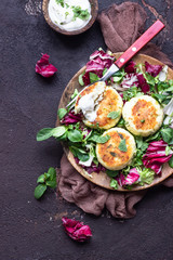 Cottage cheese pancakes or syrniki with cheese, green onion, dill and parsley served with salad mix and sour cream with mint.