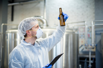 Technologist industrial worker holding beer bottle in brewing beverage production.