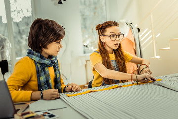 Red-haired girl having many creative ideas while designing clothes