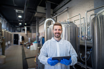 Portrait of young smiling technologist with tablet in production plant.