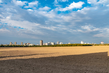 Fototapeta na wymiar View over a harvested field to the satellite city Gropiusstadt in Berlin-Neukoelln illuminated by the sun.