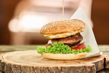 Hamburger with beef, cheese, tomato and lettuce. Big hamburger on a wooden surface.