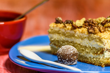 Walnut sponge cake slice photographed close-up on a turquoise plate, on wooden background.
