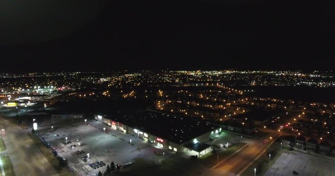 Flying Over Shopping Plaza Towards Neighborhood And City Lights At Night Aerial View