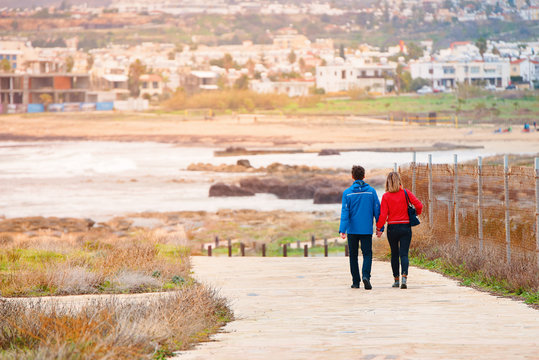 Adult man and woman stroll along the promenade in the afternoon