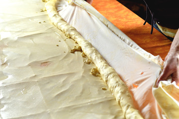 Fototapeta na wymiar Rolling dough for strudel with curd cheese on a kitchen table