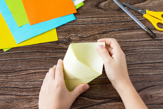The child folds the parts Origami toy made from paper puppets cat. Handmade. Project of children's creativity, handicrafts, crafts for kids.