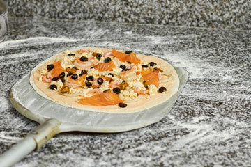 Pizza on pizza shovel. Pizza on shovel is ready to be baked in oven.
