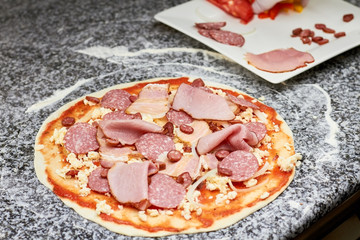 Different sliced cold meats with cheese on dough. Hams on pizza basis.
