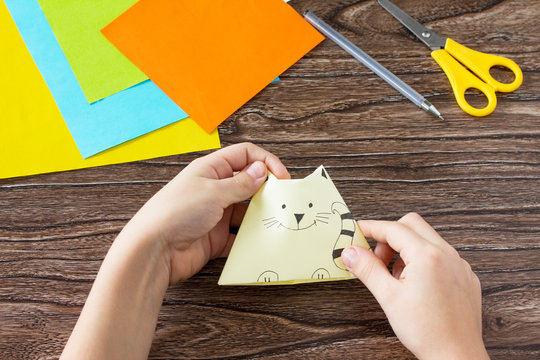 The child draws the parts Origami toy made from paper puppets cat. Handmade. Project of children's creativity, handicrafts, crafts for kids.