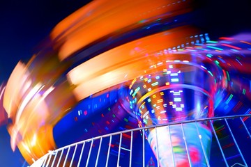 Abstract motion blur lighting and multicolored of carousel is spinning in amusement park,close up...