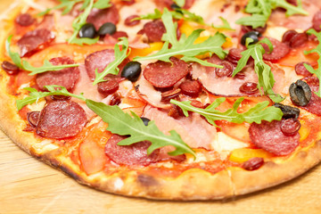 Close up baked pizza quattro carne. Delicious pizza with arugula.