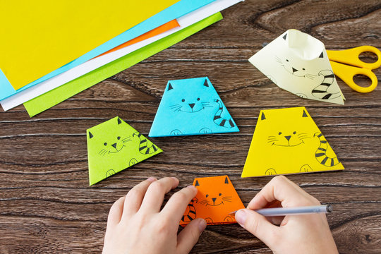 The child folds the parts various Origami toy made from paper puppets cat. Handmade. Project of children's creativity, handicrafts, crafts for kids.