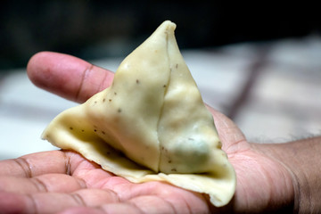 A male hand holding a samosa
