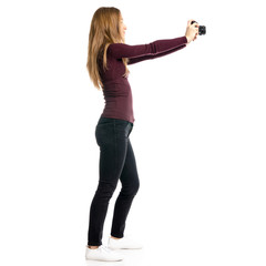 Woman in black jeans and shirt with camera in hand on white background isolation, back view