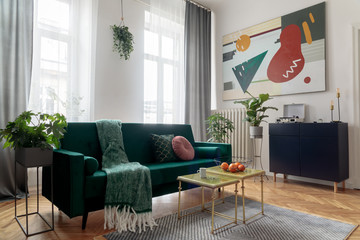 Sunny and bright luxury home interior with design velvet sofa, armchair, tables, pouf, commode and...