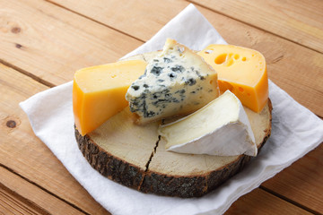 Cheese on white cloth. Camembert, hard yellow cheese, dorblu on wooden boards. Dairy products on white napkin. Copy space