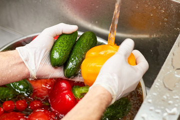 Yellow bell bepper and cucumbers washing by tap water. Vegetables in a kitchen sink. - Powered by Adobe
