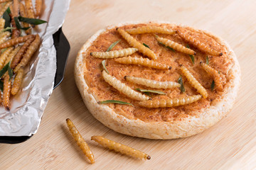 Bamboo worm (Bamboo Caterpillar). Food insects for eating as food. Bakery baked bread made of cooked insect and baking tray on wood background is good source of protein edible. Entomophagy concept.