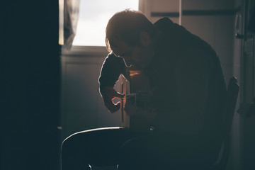 Backlight of man playing Spanish guitar.