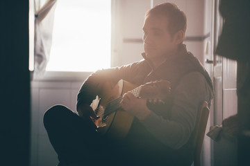 Backlight of man playing Spanish guitar.