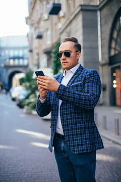 young stylish man holding a mobile phone in the city center