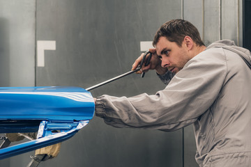 Employee car body painting shop eliminates a small metal defect