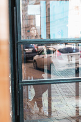 Obraz na płótnie Canvas street photo of a girl with dreadlocks behind a glass door