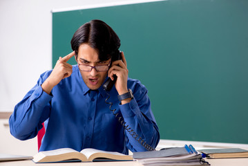 Young male teacher in front of chalkboard  