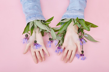 Hands and spring flowers are on a pink table skincare. Nature Cosmetics for hand skin care, a means to reduce wrinkles on hands, moisturizing. Natural cosmetics from flower extract, beauty and fashion