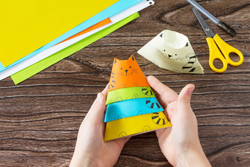 Origami toy made from paper puppets cat. Glue, scissors and paper on a wooden table. Children's art...