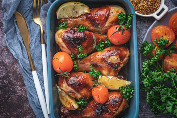 baked chicken legs in a barbecue sauce with tomatoes, top view
