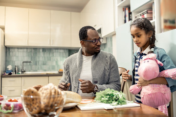 Loving father making sandwiches for snack sitting near daughter