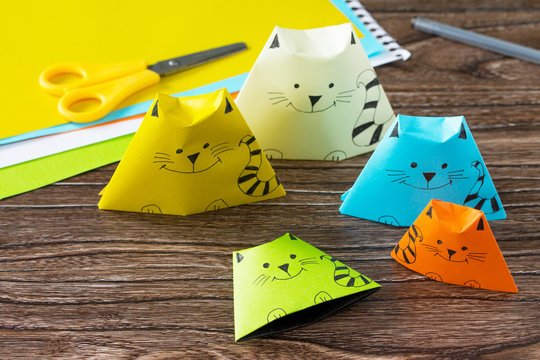 Origami toy made from paper puppets cat. Glue, scissors and paper on a wooden table. Children's art project craft for kids. Craft for children. Copy space.