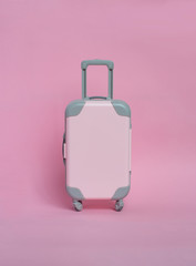Pink suitcase on a pink background. Minimalism