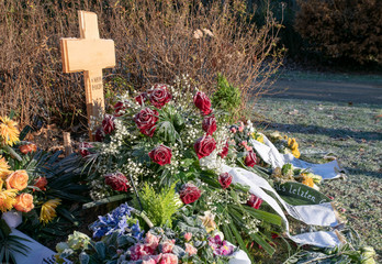 Kränze mit Schleifen und Holzkreuz im Frost 