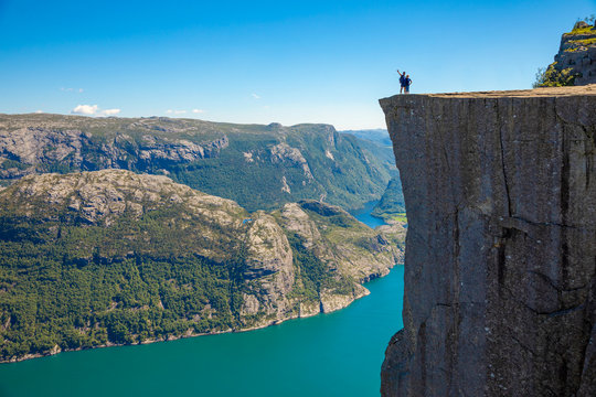 Hiker standing on Preikestolen and looking on the fjerd, Preikestolen - famous cliff at the Norwegian mountains