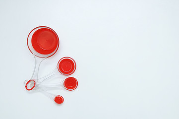 Red plastic measuring spoons for cooking. White background. View from above.